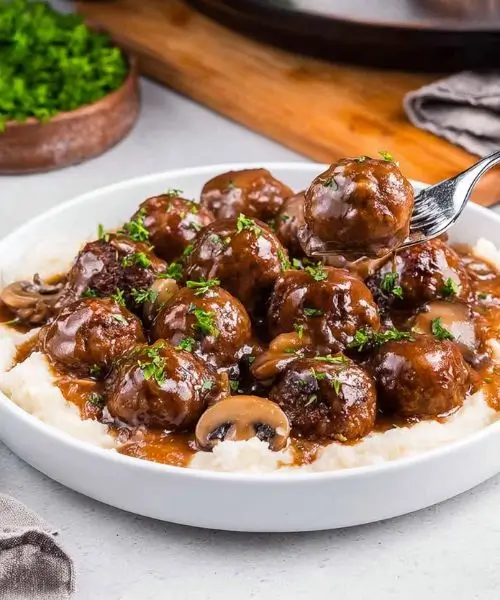 Slow cooker Salisbury steak meatballs in rich brown mushroom gravy served over mashed potatoes.