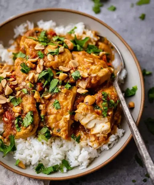 thai peanut chicken served over rice with cilantro and chopped peanuts