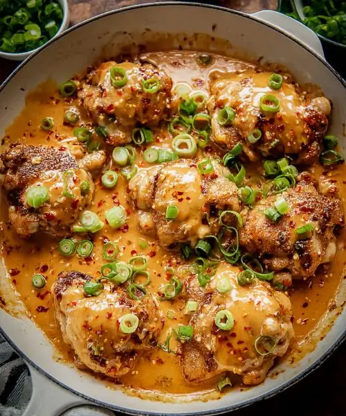 Skillet Bang Bang Chicken Thighs in creamy sweet chili sauce topped with green onions